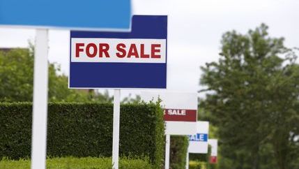 Blue for sale board in a row of agency boards