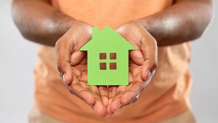 Green home model house being held in hands