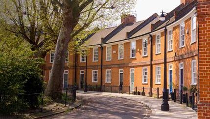 Classic British crescent with restored Victorian red brick houses on a local road with small garden in front