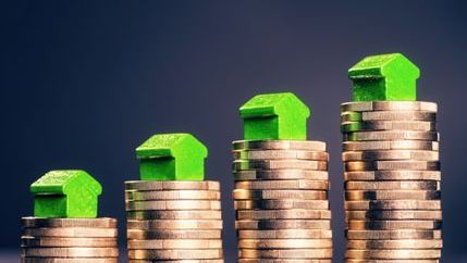 Green model houses on stacks of pound coins